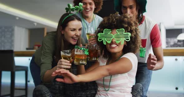 Diverse group of happy friends celebrating st patrick's day drinking beers at a bar alt