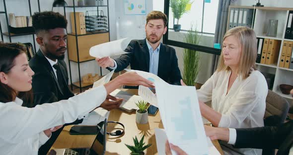 Team Working Together with Financial Statistics in Boardroom and Giving Each Other documents alt