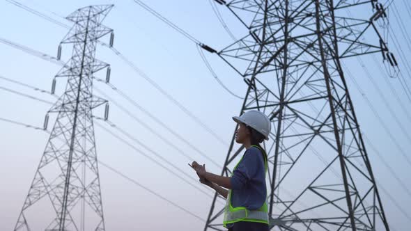 Female electrical engineer working near to High voltage tower.