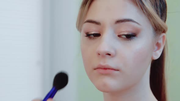 A Makeup Artist Applies Blush To the Cheeks of a Beautiful Model with a Makeup Brush