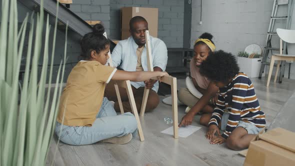 Black Family Assembling Wooden Chair Together alt