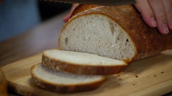 man cuts pieces of bread. Whole grain fresh bread on a wooden table alt