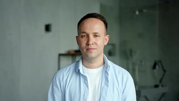 Cheerful guy with high temple in blue shirt looks straight alt