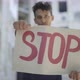 Rack Focus Goes To STOP Banner Raised By Serious Young Man in Slum. Portrait of Concentrated Mixed - VideoHive Item for Sale
