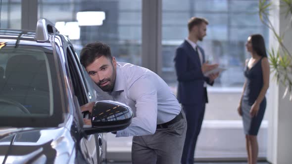 Joyful Male Buyer Looking Inside Car at Dealership alt