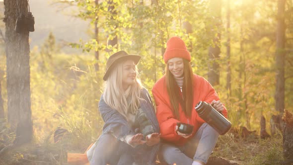 Young Friends Relax Comfortably and Drink Hot Tea on Autumn Evening in the Open Air alt