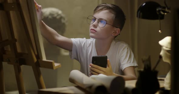 Boy Using Smartphone and Drawing alt