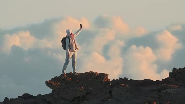 Happy Woman at Peak on Video Call with Friends at Cinematic Clouds Background 5G alt