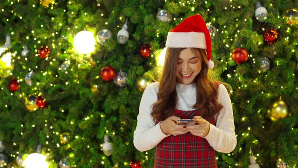 happy woman using smartphone with Christmas tree, x-mas celebrating