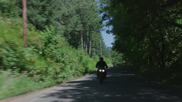 Tracking shot of man riding motorcycle on country road.  Fully released for commercial use.