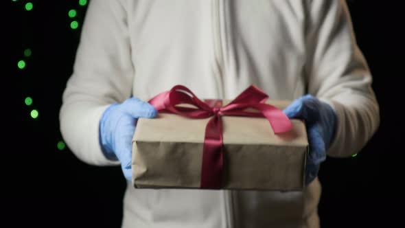 Closeup on Child's Hands Giving Box with Red Ribbon