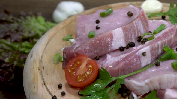 Raw steaks on a rotating wooden plate