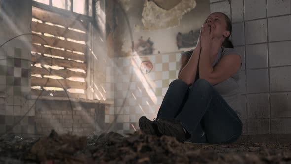 Depressed woman crying while sitting on floor in abandoned building alone alt