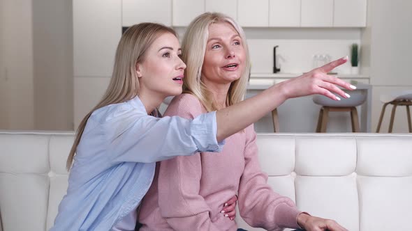 Two Women Beautiful Smiling Senior Mother with Her Adult Daughter Sitting on Sofa at Home and alt