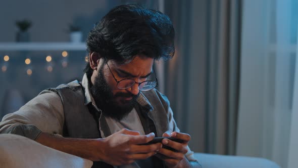Closeup Focused Motivated Inspired Arabian Indian Man Bearded Guy in Glasses Playing Mobile Game alt