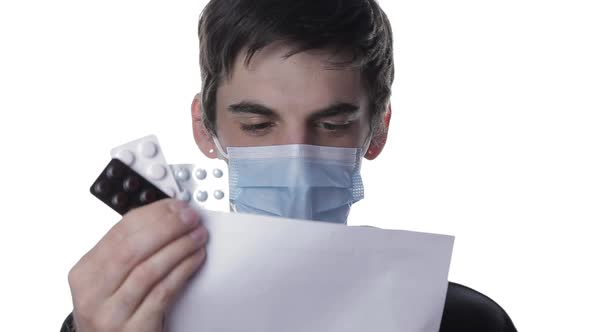 Portrait of a Young Man in a Medical Mask Who Reads a Prescription From a Doctor