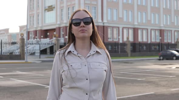 Beautiful Young Girl with Glasses Walks Through the City and Looks Around