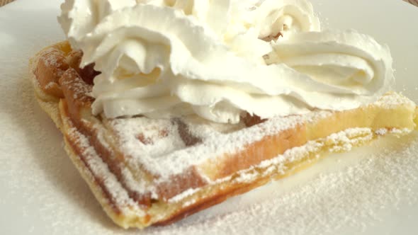Preparation of waffles. Whipped cream is applied to the waffles. alt