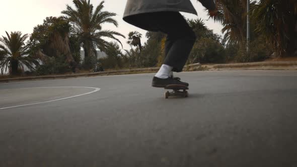 Man skates around the bend on the road, downhill, low angle gimbal shot alt