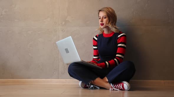 woman with laptop computer sitting on a floor.
