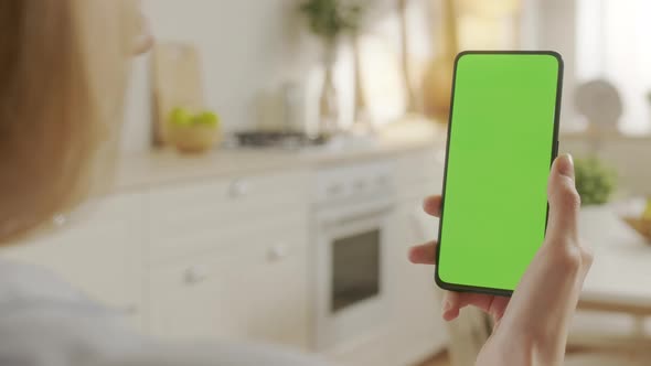 Back View of Woman at Kitchen Room Using Phone With Green Mockup Screen Chroma Key Without Track alt