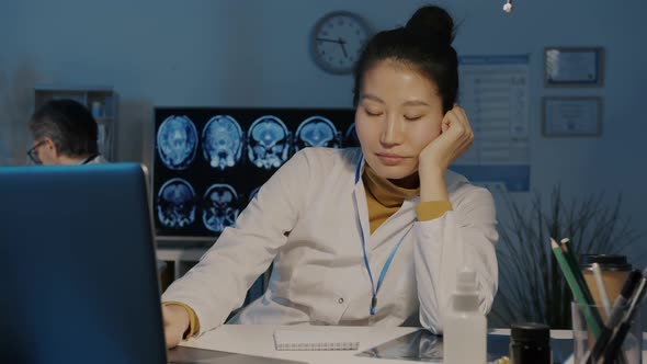 Exhausted Asian Doctor Napping Then Using Laptop Typing in Dark Office at Night alt