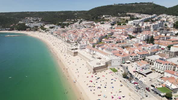 Sesimbra beach full of tourists during vacation, Aerial orbital drone shot alt