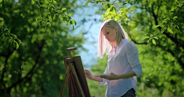 Beautiful Woman Artist Paints a Picture with Paints on Canvas Plener alt