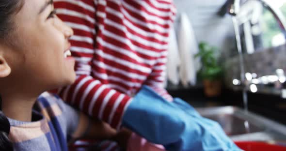 Mother and daughter washing dishes in kitchen 4k alt