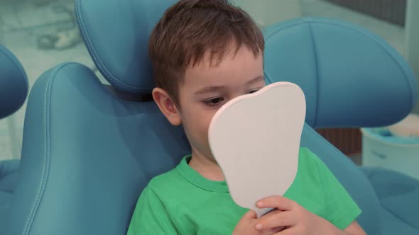 Child in a Dentist's Office Sits in a Chair a Boy in a Dentist's Office in a Clinic Looks in the alt