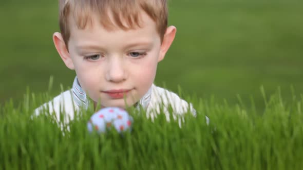 Young boy finds Easter egg in grass alt