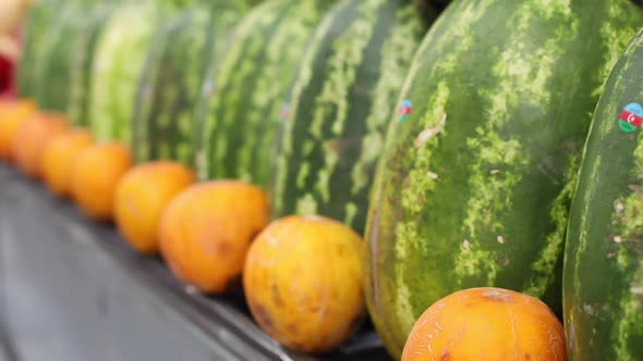 Close Up Video of Large Juicy Green Watermelons Stand on the Counter, Between Them Oranges