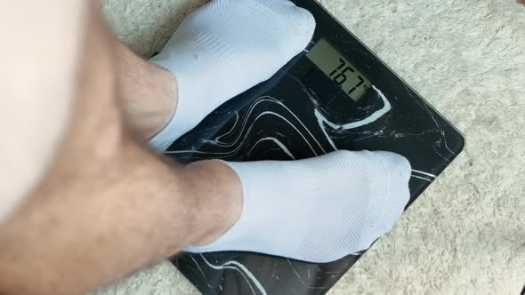 Man Weight Control, Male Stand On Floor Scales, Man 76.7 Kg, Obese And Overweight Man.
