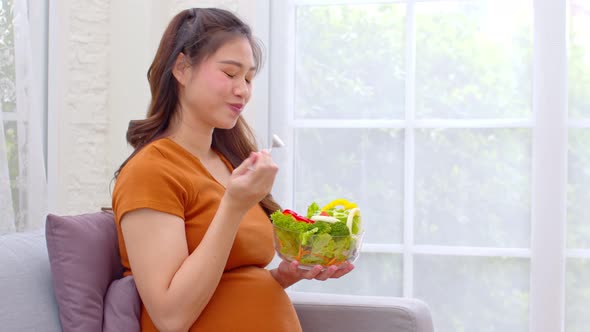 Pregnant Young Asian woman eat mixture of vegetables Fresh Salad at home alt