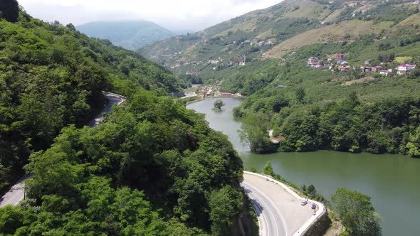 Mountain roads adjacent to the lake and clouds interfering with the tops of the mountains alt