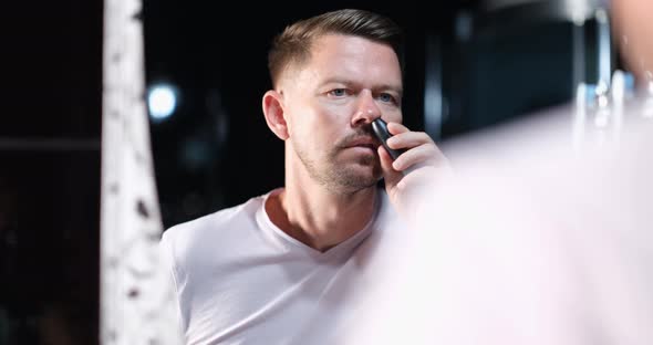 Young Man Removing Hair From His Nose with Trimmer in Front of Mirror  Movie alt