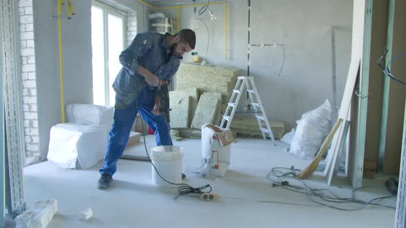 Male Builder Mixing Stucco with Drill in Bucket