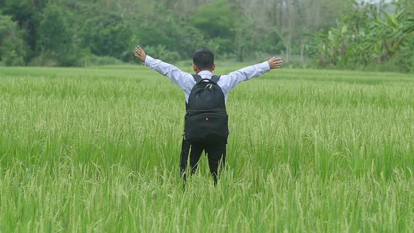 Boy Standing In Rice Field with Arms Outstretched alt