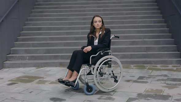 Portrait of Handicapped Young Woman Ceo Executive in Suit Sitting in Wheelchair Near Office Building alt