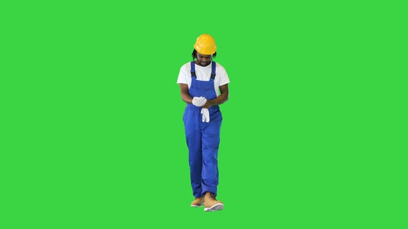 Construction Worker Putting on Gloves While Walking on a Green Screen Chroma Key alt