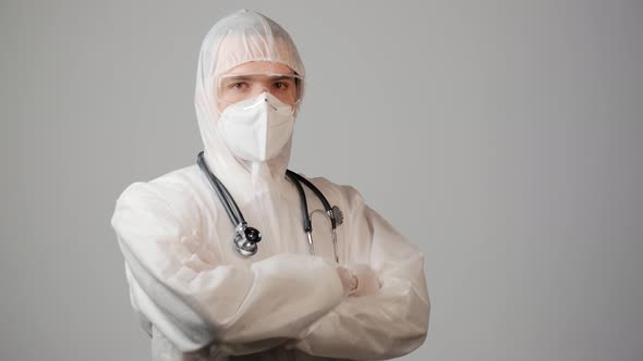 A Male Doctor in a Protective Medical Suit and Looks at the Camera