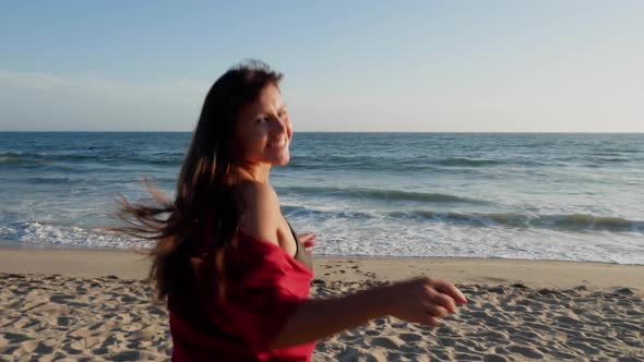 Attractive and playful woman running along the beach alt