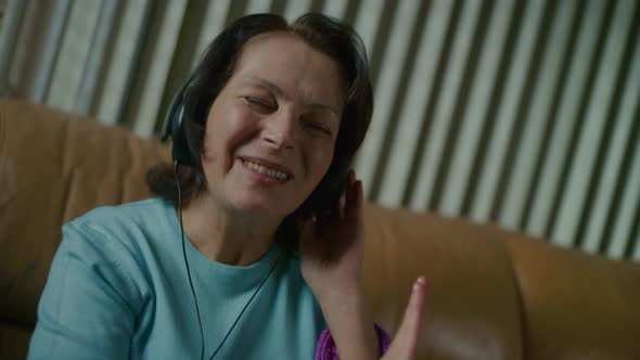 Elderly Woman in Headphones is Dancing to Dynamic Music and Smiling