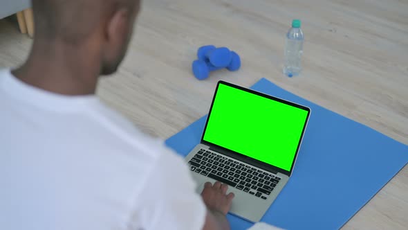 African Man Using Laptop with Chroma Key Screen on Yoga Mat alt