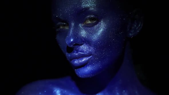 Portrait of Beautiful Woman with Blue Sparkles on Her Face