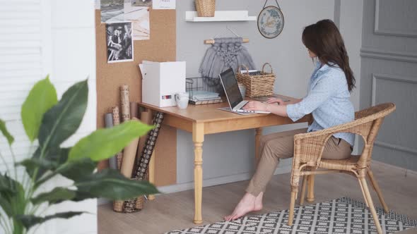Designer Works in a Home Studio. Young Woman in Casual Wear Is Using a Laptop alt