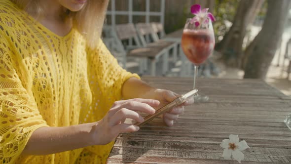 A Pretty Young Woman with Vitiligo Pigmentation Sits By the Beach Chatting on the Phone alt