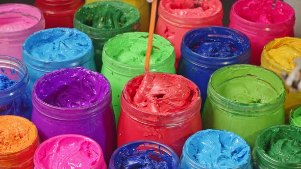 Use A Spoon To Stir The Red Paint In The Bucket alt