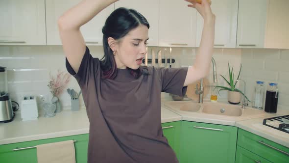 Young Woman in Tshirt Make Fun Singing and Dancing While Baking at Home Kitchen