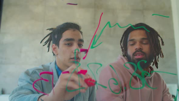 Male Freelancers Drawing Graph on Glass Board alt